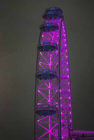 London Eye Illuminated in Pink Lighting Against Cloudy Night Skyの写真素材