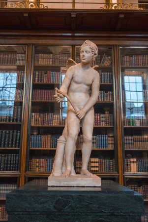 Marble Statue of Winged Figure with Bow in a Library Settingの写真素材