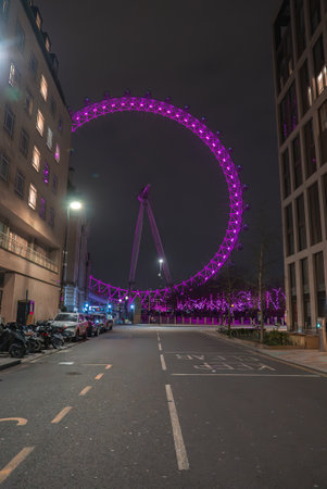 London Eye Illuminated in Purple Lights at Night with Cityscapeの写真素材