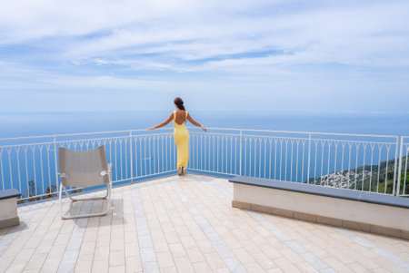 Woman in Yellow Dress on Terrace Overlooking Tyrrhenian Seaの写真素材