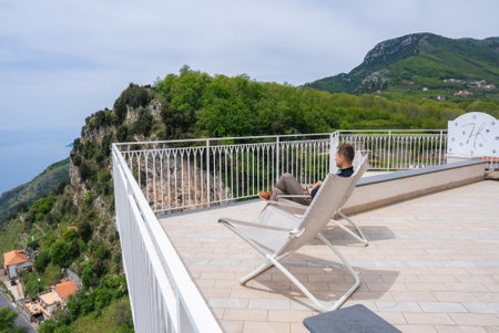 Man Relaxing on Terrace Overlooking Hills and Tyrrhenian Sea in Amalfiの写真素材
