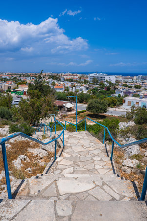 Stone Staircase with Blue Railings Overlooking Coastal Town in Cyprusの写真素材