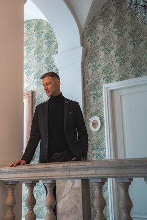Man in Black Turtleneck Near Stone Balustrade in Elegant Hotel Interiorの写真素材