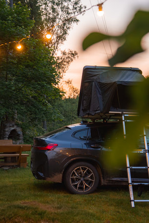 Modern SUV with Rooftop Tent and String Lights in Forest Settingの写真素材