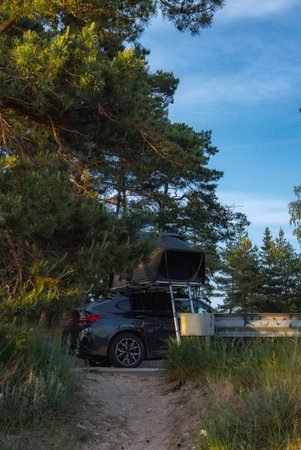Modern SUV with Rooftop Tent Parked in a Forested Areaの写真素材