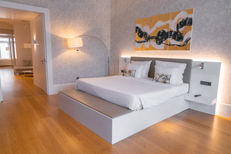 Modern Hotel Room with White Platform Bed and Abstract Artworkの写真素材