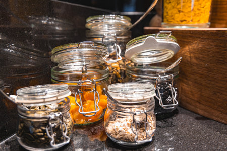 Glass Jars with Dried Goods on Glossy Black Countertop in Luxury Settingの写真素材