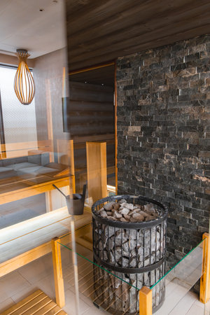 Luxurious Sauna Interior with Wooden Benches and Stone Wallの写真素材