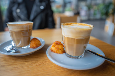 Two Lattes with Pastries on a Wooden Table in Utrecht Cafe