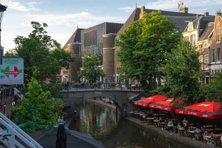 Canal in Utrecht with Stone Bridge, Greenery, and Outdoor Seatingの写真素材