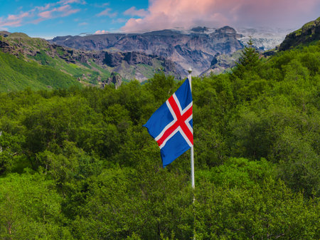 Icelandic Flag Amidst Greenery with Cliffs and Glaciers in Backgroundの写真素材
