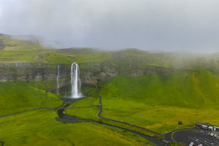 Seljalandsfoss Waterfall with Mist and Green Hills in Icelandの写真素材