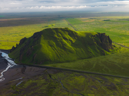 Lush Green Hill with Streams and Road in Icelandic Landscapeの写真素材