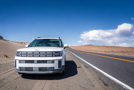 White SUV Parked on a Long Desert Road in Nevadas Arid Landscapeの写真素材