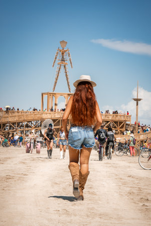 Woman Walking Toward Burning Man Effigy in Nevada Desert Festivalの写真素材