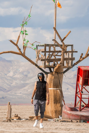 Man Walking Near Wooden Tree Art Installation in Nevada Desertの写真素材