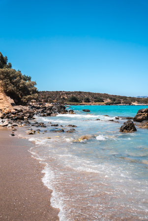 Serene Beach with Turquoise Waters and Rugged Coastline in Creteの写真素材