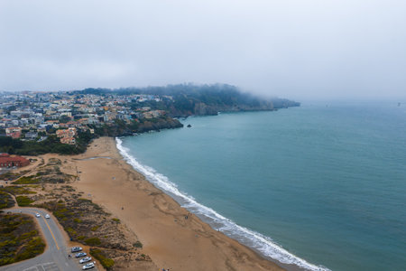 Coastal View with Sandy Beach, Colorful Houses, and Forested Hillの写真素材