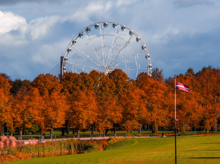 Ferris wheel and Latvian flag in Riga park during golden autumnの写真素材