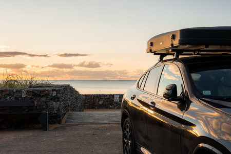Black luxury SUV at coastal lookout with cargo box at sunset