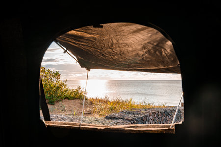 Rooftop tent view toward calm ocean and dunes at golden hourの写真素材