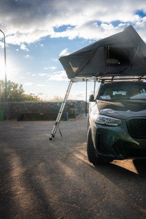 Luxury SUV with rooftop tent by stone seawall in late afternoon lightの写真素材