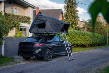 Luxury SUV with rooftop tent parked on a quiet suburban streetの写真素材