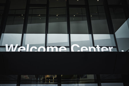 Modern glass facade with Welcome Center sign under overhang
