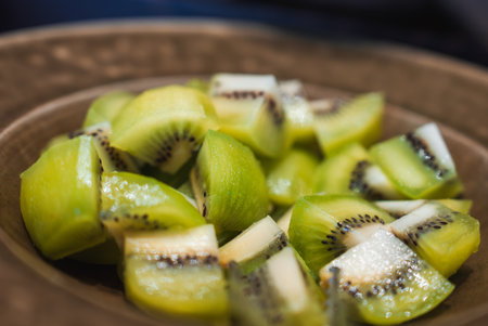 Close view of kiwi pieces on a rustic brown plate in soft lightの写真素材