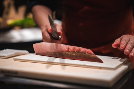 Chef slices tuna sashimi at a Japanese hotel sushi counterの写真素材