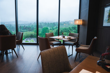 Contemporary lounge with floor to ceiling windows and forest viewの写真素材