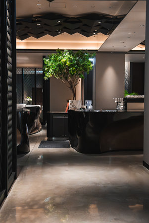 Modern Japanese hotel lobby with curved black desks and concrete floor