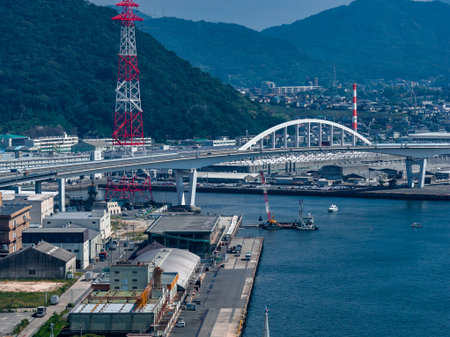 Coastal Hiroshima with white arch bridge, docks, and towers in daylightの写真素材