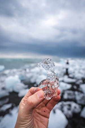 Hand holds crystal glacier shard at Icelands Diamond Beach
