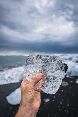 Hand holding glacial ice at Diamond Beach, Jokulsarlon, Iceland