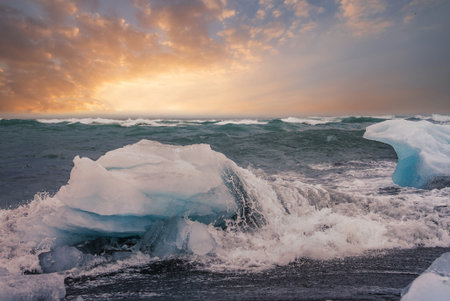 Waves meet ice on black sand at Diamond Beach, Iceland, sunset