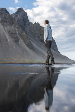 Traveler on black sand by Vestrahorn at Stokksnes peninsula