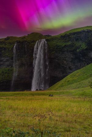 Seljalandsfoss waterfall and northern lights over basalt cliffs in Icelandの写真素材