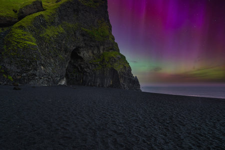 Reynisfjara black sand and basalt cave under aurora near Vik, Icelandの写真素材