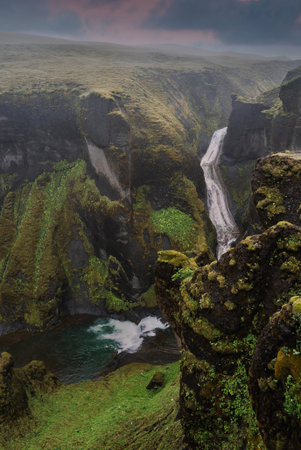 Iceland canyon at dusk with waterfall and mossy basalt cliffsの写真素材