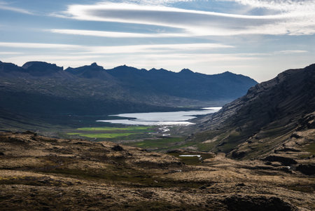 Iceland valley with basalt ridges and reflective lake in soft lightの写真素材
