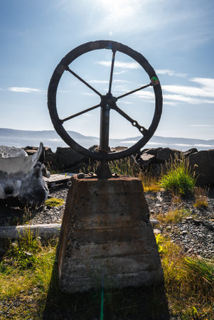 Rusted metal wheel on concrete plinth in coastal Iceland field