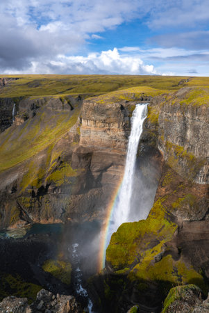 Tall waterfall with rainbow at basalt canyon in Iceland Highlandsの写真素材