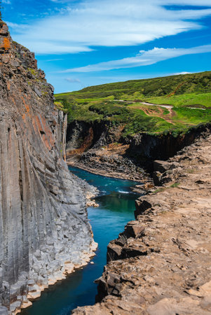 Turquoise river in Studlagil Canyon with hexagonal basalt walls, Iceland