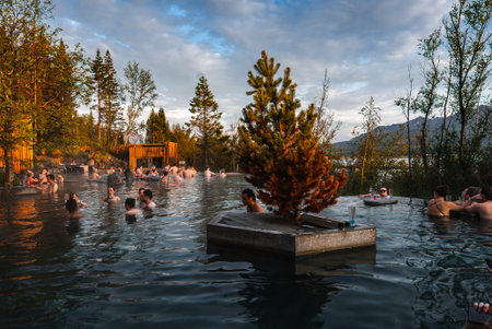 Wide outdoor geothermal pool at sunset with central conifer islandの写真素材