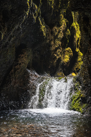 Mossy basalt grotto waterfall and clear pool in South Coast Icelandの写真素材