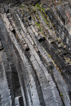 Basalt columns with hexagonal edges on a rugged volcanic cliff in Iceland