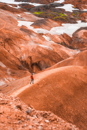 Hiker crosses rhyolite hills and steam vents in Iceland Highlandsの写真素材