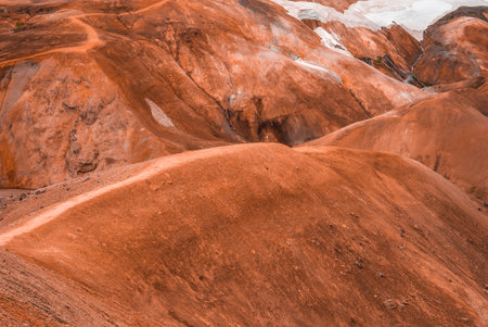 Rust orange rhyolite hills with snow in Iceland highlands, summer light