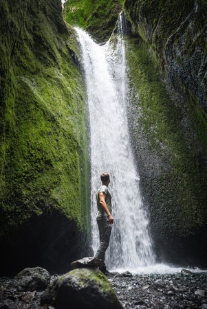 Traveler at Gljufrabui waterfall within shaded basalt slot gorgeの写真素材